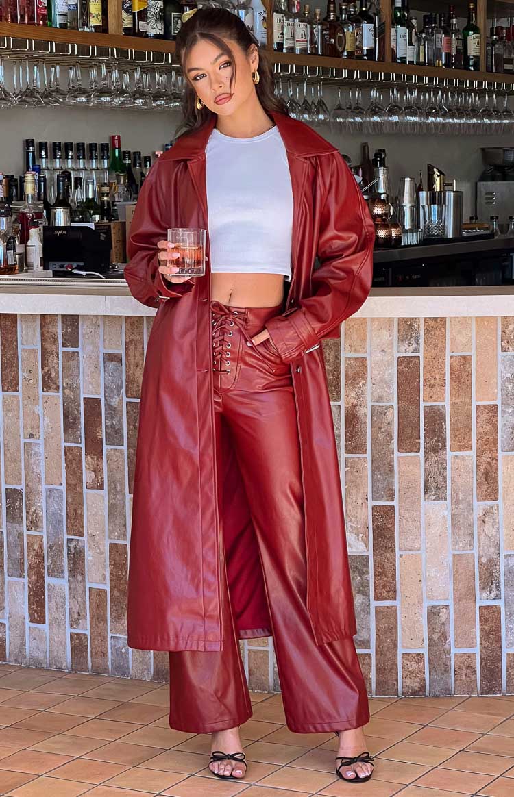 Full length red PU trench coat worn open, showing its wide collar and long sleeves, paired with matching lace-up pants