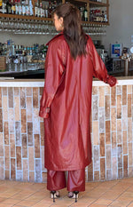 Back view of the long, relaxed fit red PU trench coat with buckle details on the sleeve cuffs