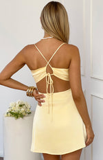 Rear view of a yellow satin mini dress with criss-cross spaghetti straps and a ruched tie-back detail