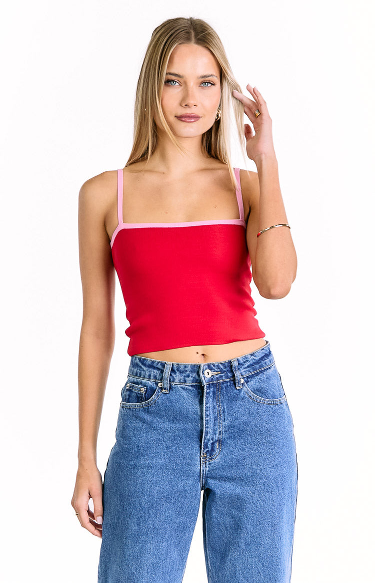 Front view of a red knit cropped top with a square neckline and thin pink contrast spaghetti straps and pink trim