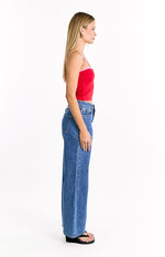 Side view of a red knit top with pink trim on the neckline and thin straps, showing its cropped length