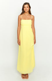 Front view of a yellow maxi dress with a straight neckline, thin spaghetti straps, and a tie-side detail at the waist