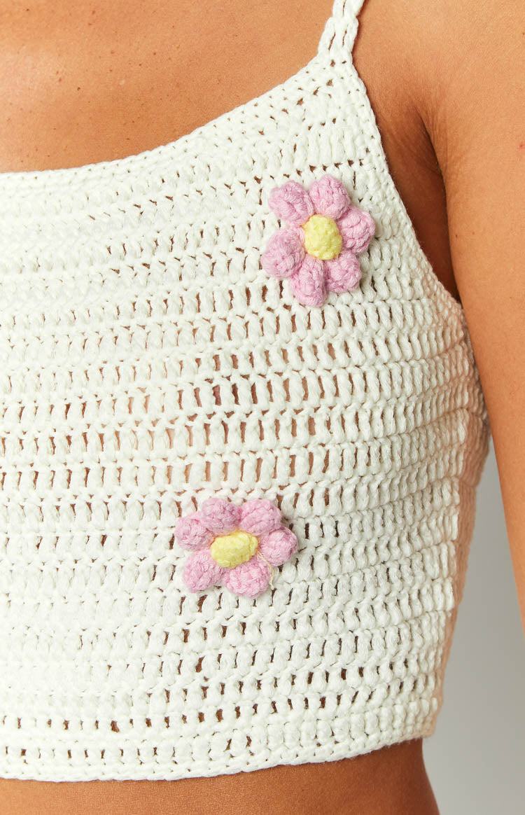 Close-up of the white open-knit crochet crop top with two pink and yellow flower appliques