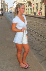 Side view of a white collared top with a deep V-neck and short puff sleeves