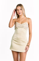 A sleeveless cream colored mini-dress with a heavily beaded and sequined bodice a satin-like skirt and a sweetheart neckline with thin spaghetti straps.