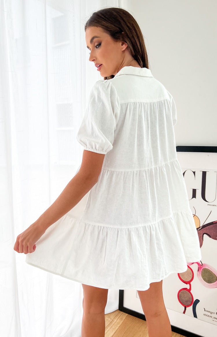 Rear view of a white linen tiered dress with short puffed sleeves and gathered back yoke