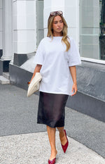 Front view of a black sheer organza midi skirt with a straight silhouette, subtle transparency, and a smooth, fluid drape