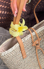 Yellow frangipani flower clip showing translucent petals, darker yellow center, and the claw mechanism attached to a strap