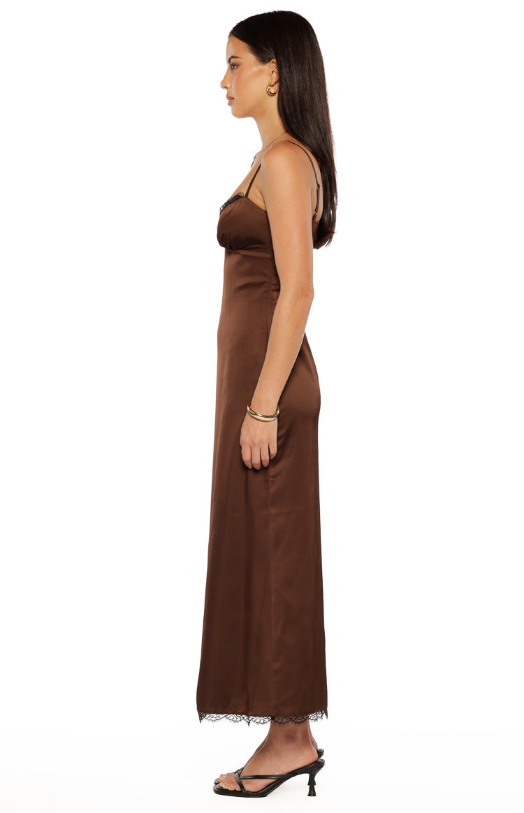 Side view of a brown satin midi dress with thin spaghetti straps and black lace trim on the neckline and hem
