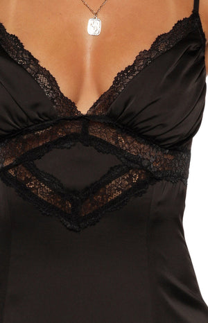 Close-up of the black satin maxi dress showing the V-neckline with lace trim and sheer lace panel with a diamond insert