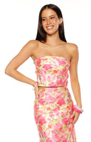 Our model wearing a strapless crop top in a pink coral and yellow floral print featuring a horizontal band of gathered or folded fabric across the bust.
