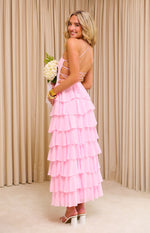 Side view of a pink ruffle maxi dress with criss-cross back straps, side cutouts, and tiered skirt