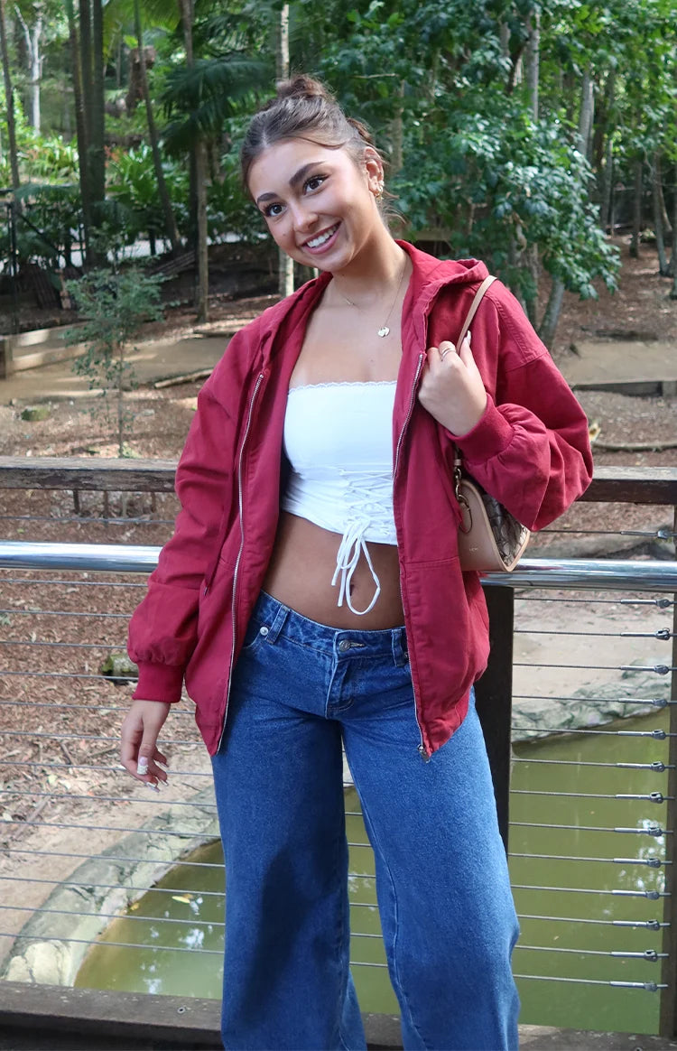 Washed red oversized hooded jacket worn open with a front zipper and voluminous long sleeves