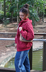 Side view of a washed red oversized hooded jacket with elasticated cuffs and hem