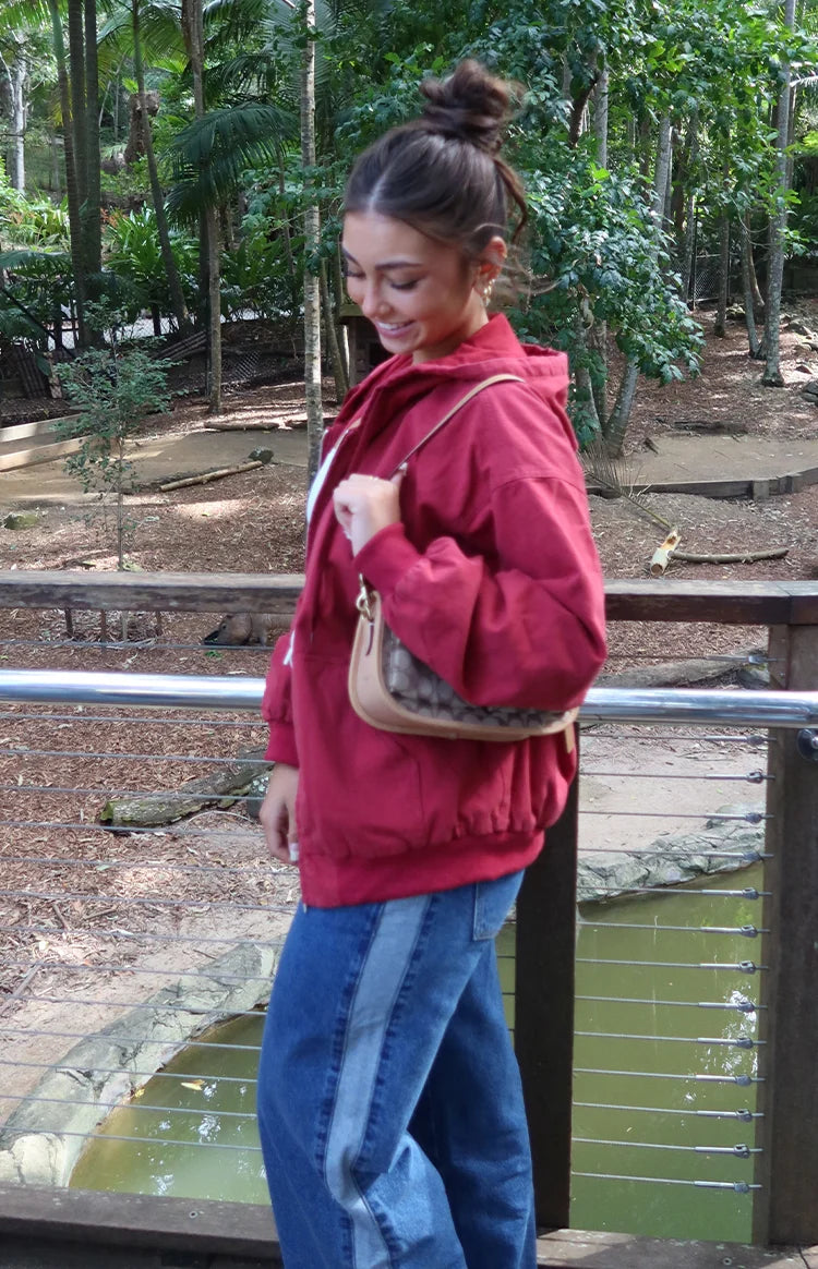 Side view of a washed red oversized hooded jacket with elasticated cuffs and hem