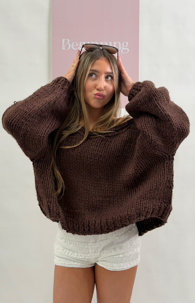 Chocolate brown chunky knit cardigan with a wide boat neckline worn off-shoulder and voluminous long sleeves