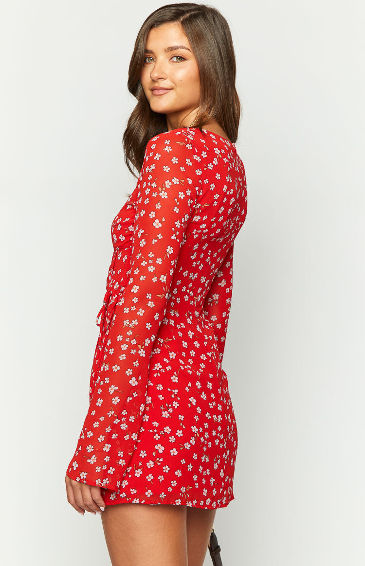 Side view of a red floral long sleeve mini dress with a ruched bodice detail and a mini hemline