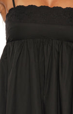 Close-up of the black mini dress showing eyelet embroidery and floral details on the bodice with a gathered empire waist