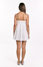 Rear view of a white mini dress with thin spaghetti straps, a fitted bodice, and a flowy gathered skirt