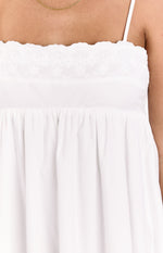 Close-up of the white eyelet embroidered bodice with scalloped edge and gathered waist of a mini dress