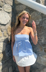 Front view of a light blue and white striped strapless top with a gathered peplum hem