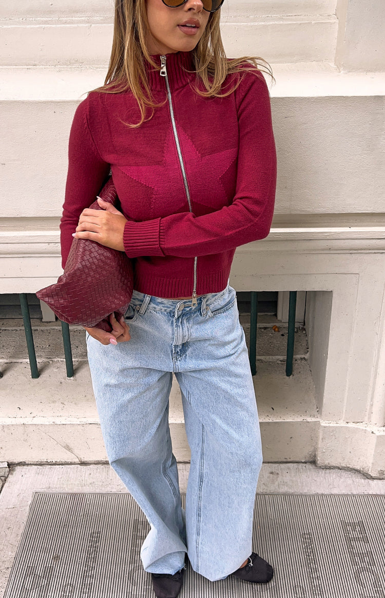 Burgundy knit zip-up sweater with a high collar, full silver zip, and textured star pattern