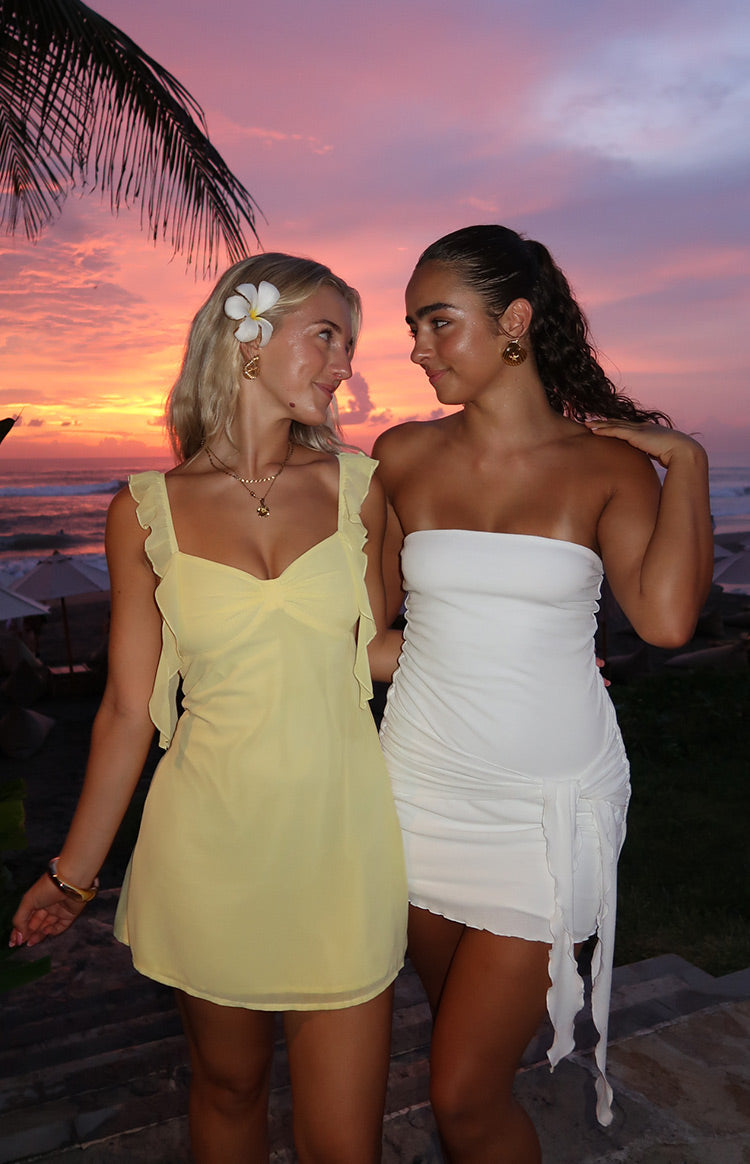 White strapless bodycon mini dress with side ruching and long flowing fabric ties at the hip