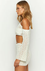 Side view of a white crochet off-shoulder long sleeve crop top with an open knit pattern