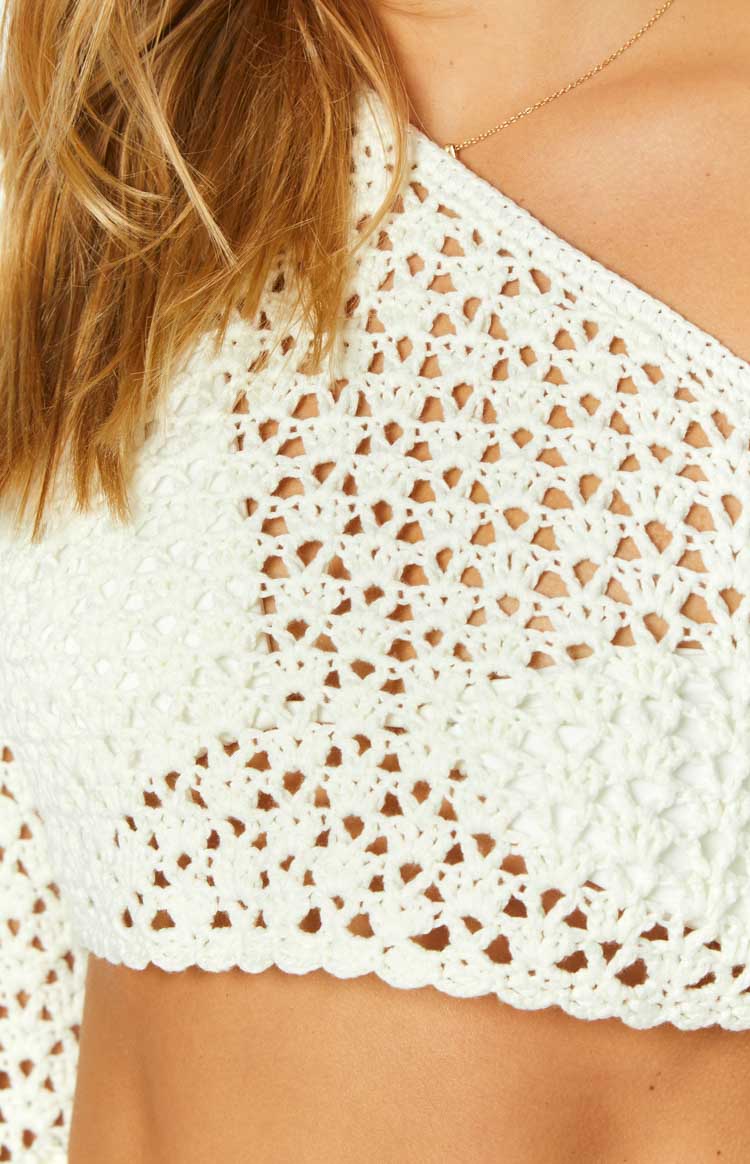 Close-up of the white crochet knit pattern with openwork design and scalloped edge