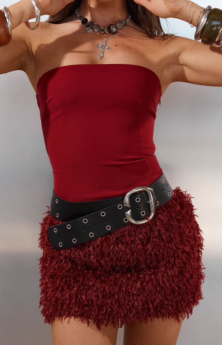 Close-up of the burgundy strapless mini dress with a smooth bodice and shaggy fur skirt