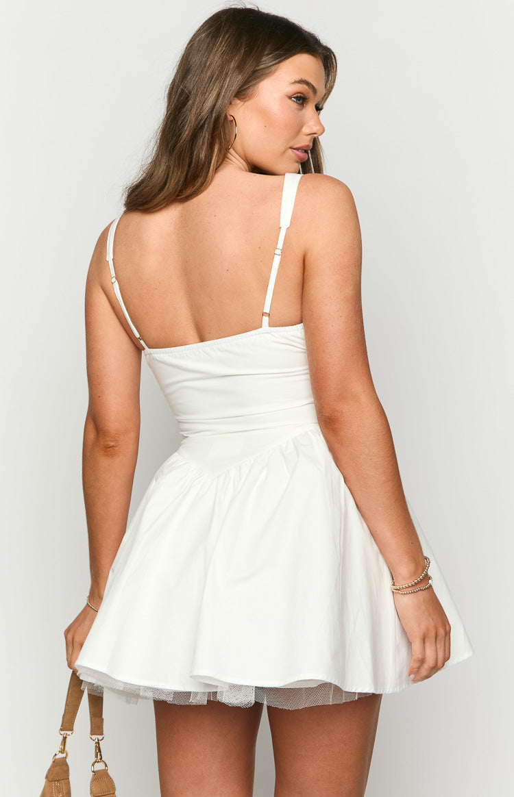 Rear-side view of a white mini dress with adjustable spaghetti straps, a fitted bodice, gathered skirt, and tulle peeking out