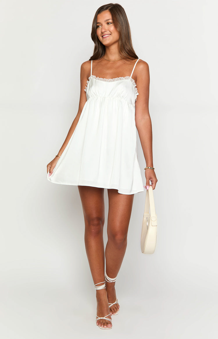 Front view of a white babydoll mini dress with delicate lace trim on the neckline and a flowy A-line skirt