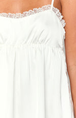 Close-up of the white lace trim, gathered waist, and invisible side zipper on a white mini dress