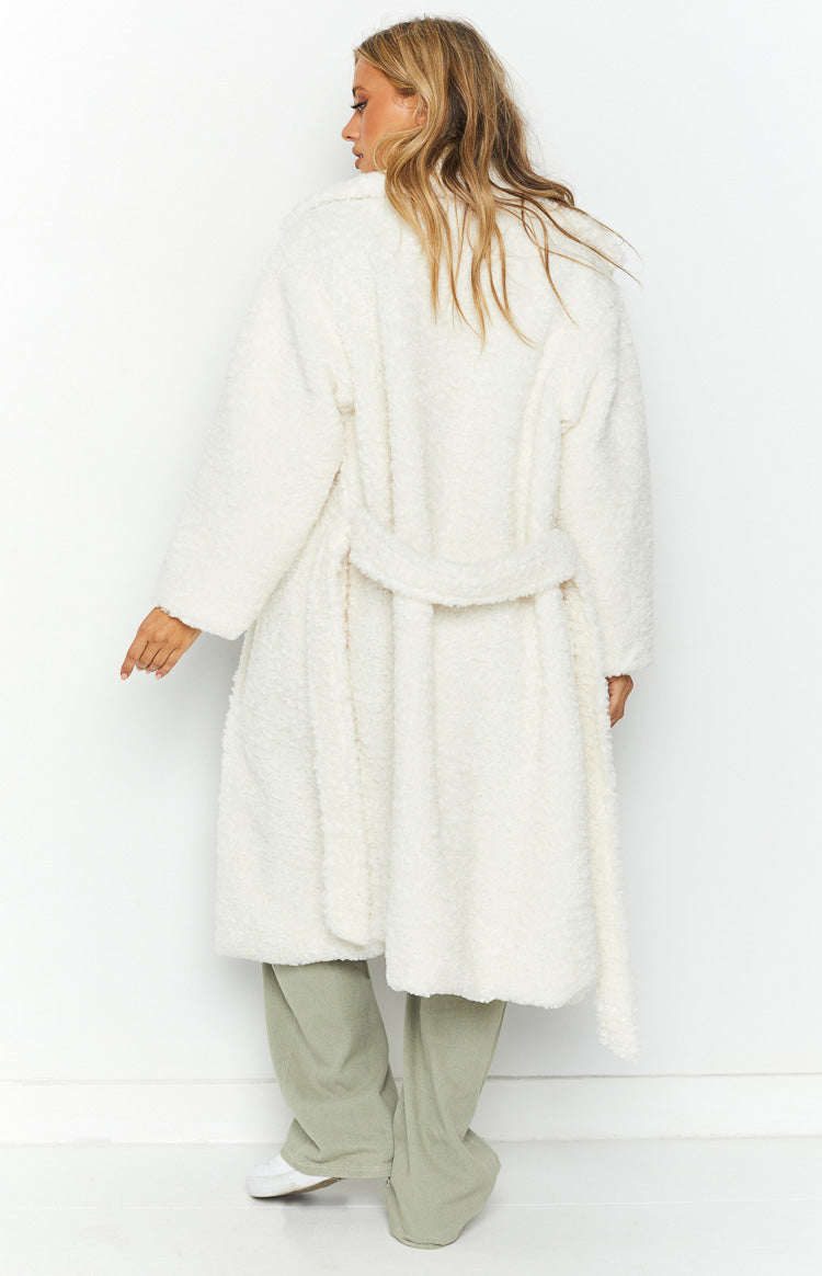 Side view of a long white teddy coat with a tie waist, wide lapels, and relaxed fit