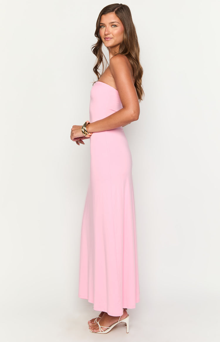 Side view of a pink strapless maxi dress with a fitted bodice and a flowing skirt