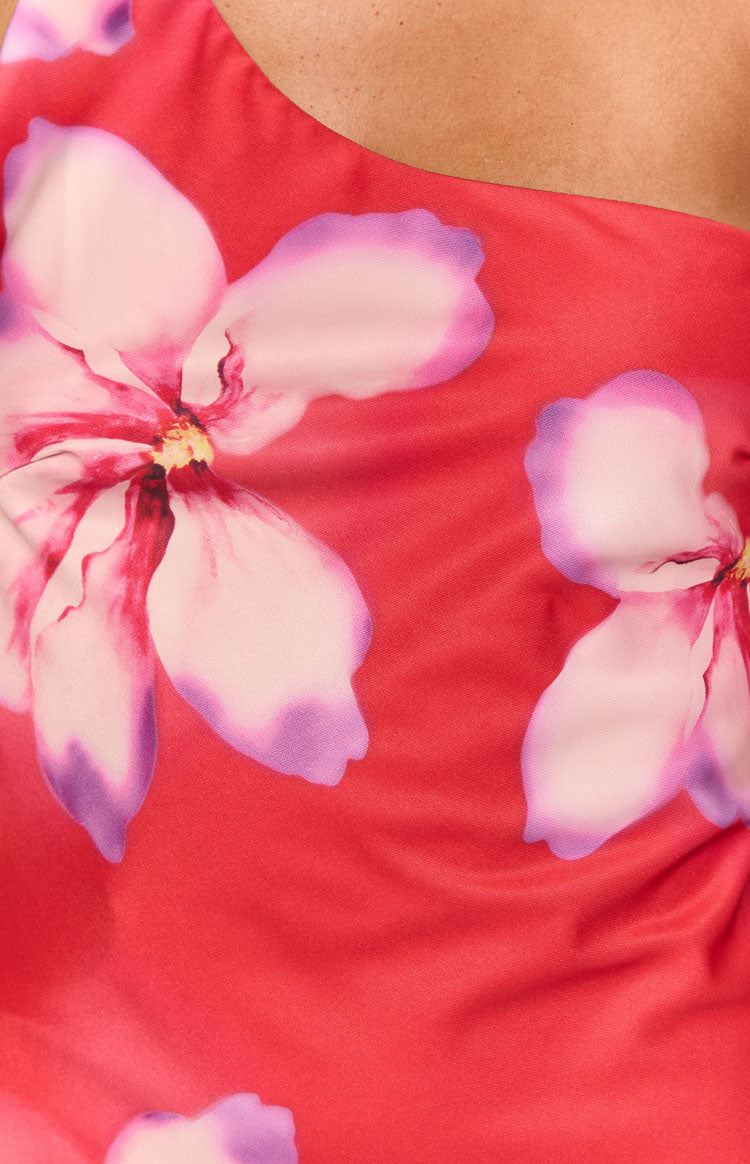 Close-up of the red fabric with large pink and purple floral print and a hint of the asymmetric neckline