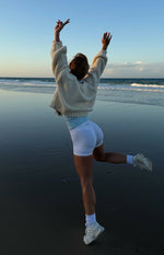 Rear view of a cream chunky knit cardigan with an oversized fit and cropped hem