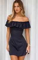 Black mini dress with white polka dots and a wide ruffled elasticated off-shoulder neckline