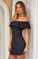 Black mini dress with white polka dots and a wide ruffled elasticated off-shoulder neckline
