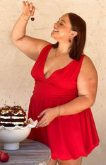 Side view of the red mini dress showing the deep wrap V-neck and gathered waist with a flowy skirt