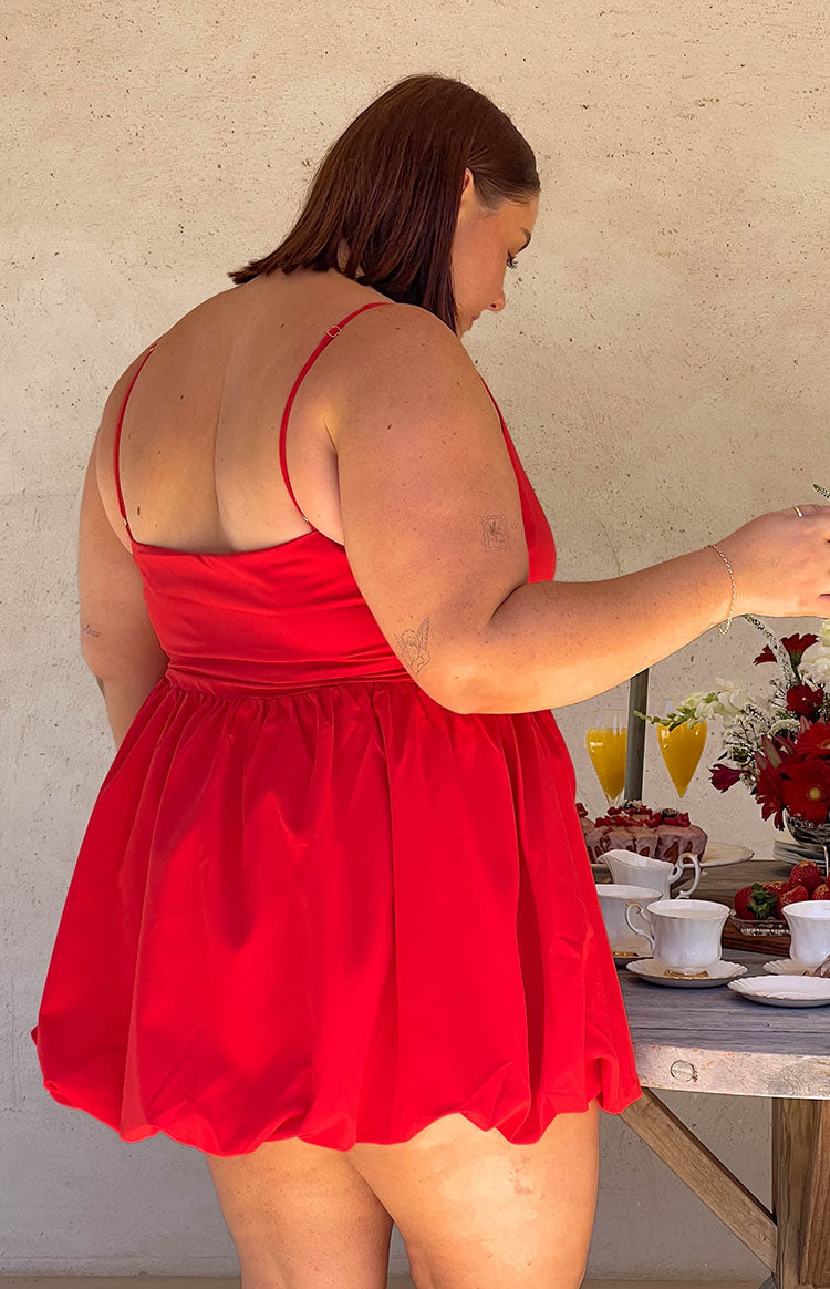 Rear view showing the straight back neckline, thin spaghetti straps, and voluminous bubble skirt of a red mini dress