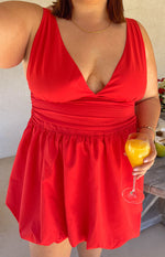 Close-up of the red mini dress showing the deep V-neckline, ruched waist, and bubble hem