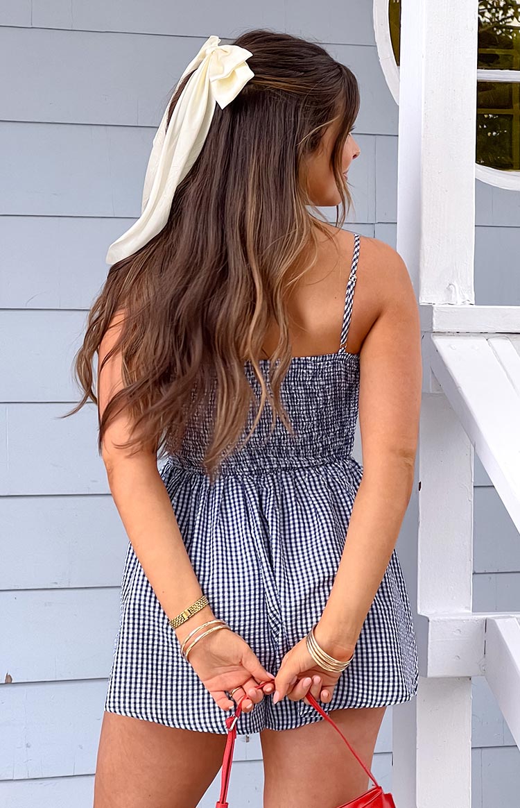 Rear view of a navy gingham playsuit with a smocked bodice and thin spaghetti straps