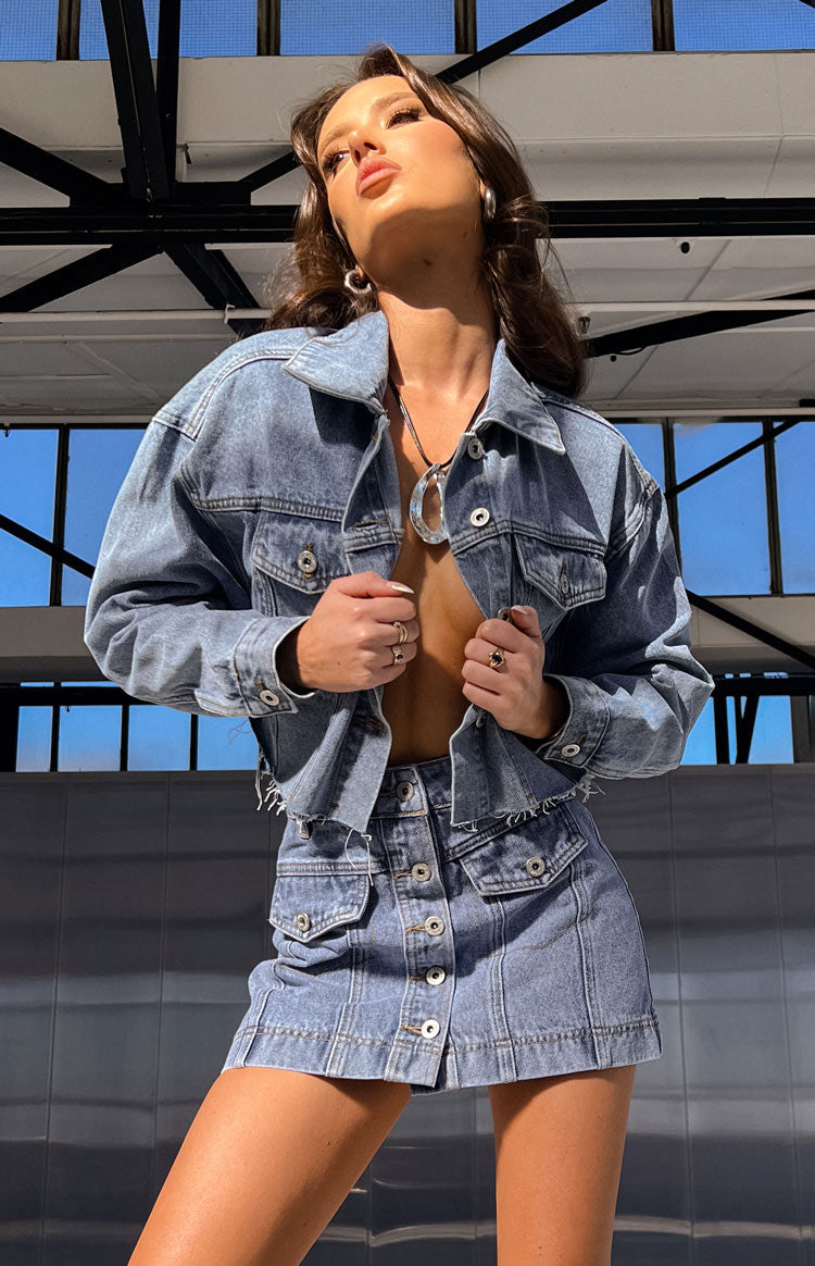 Rear view of a mid-wash denim mini skirt with prominent vertical seam detailing on the back