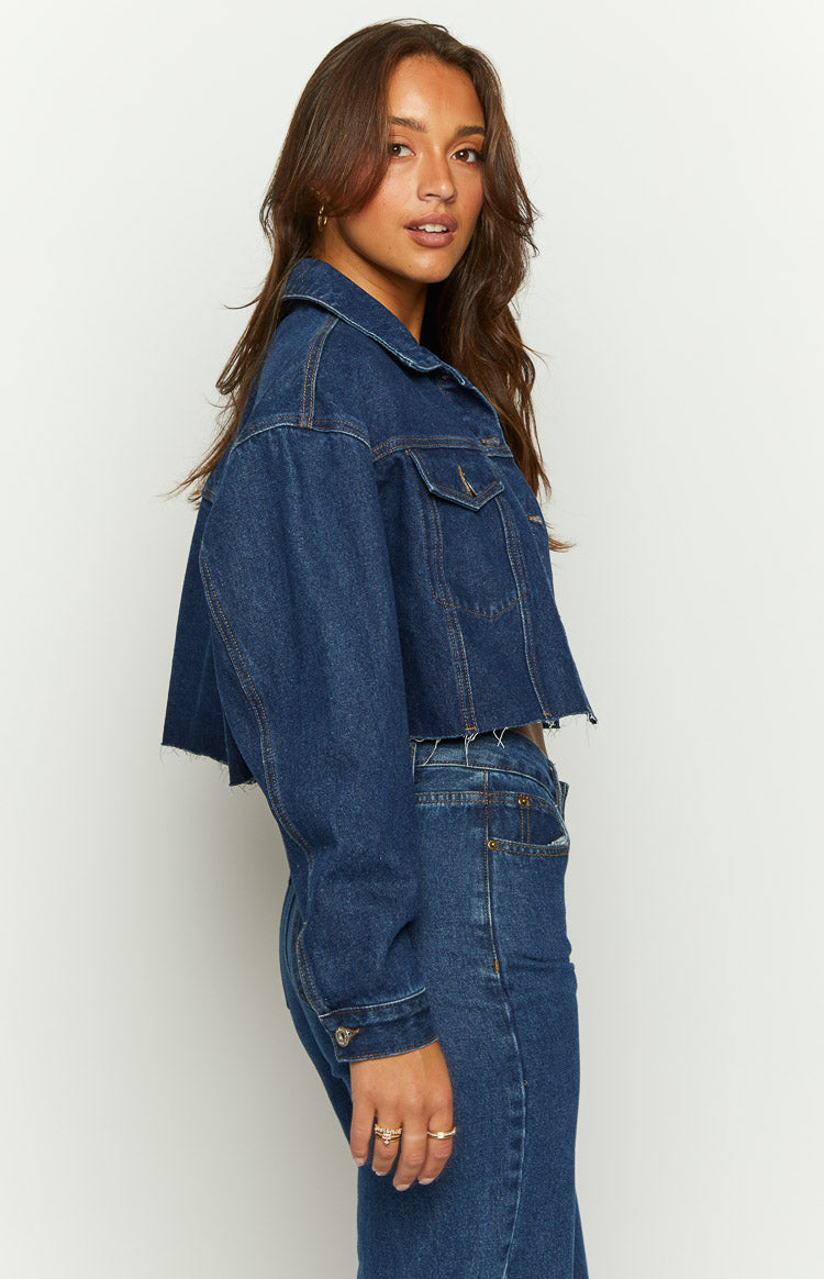 Front view of a dark wash denim cropped jacket with a raw frayed hem and relaxed fit