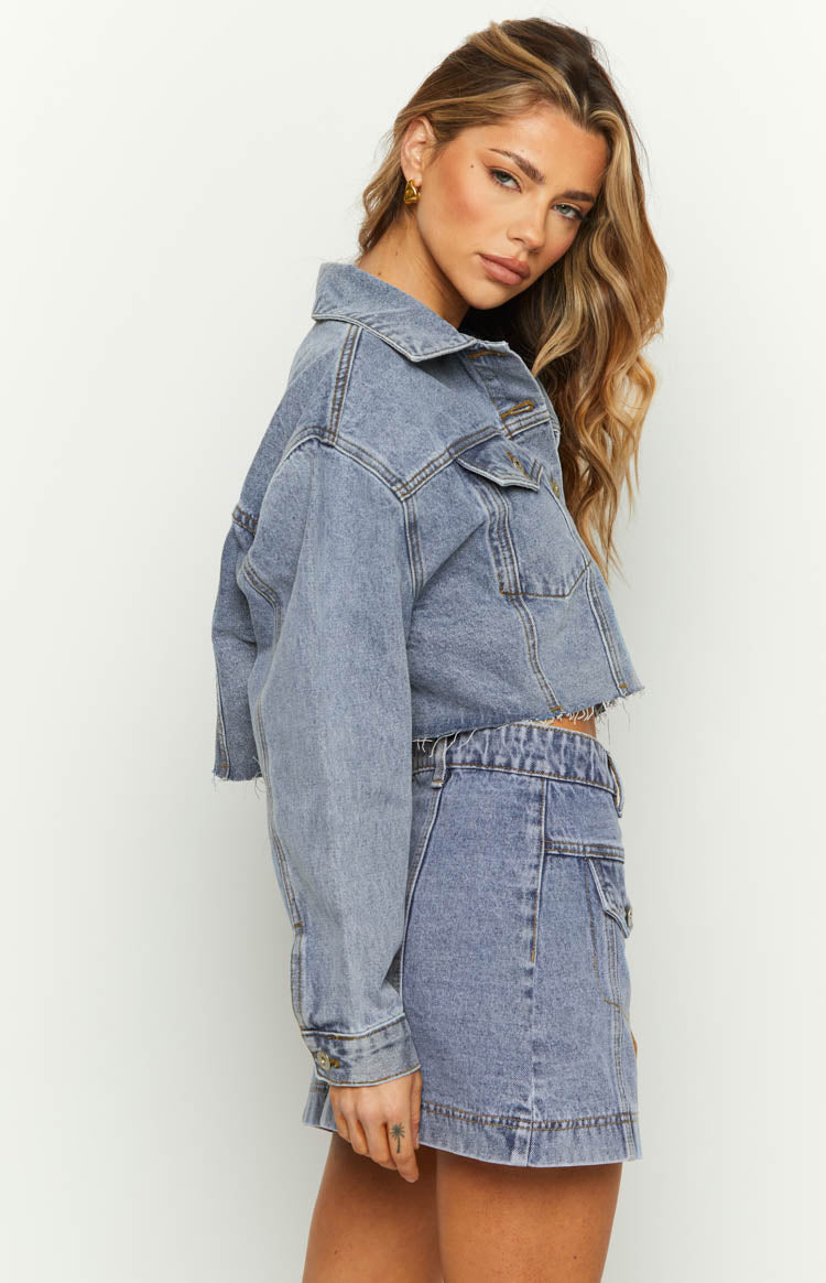 Side view of a mid wash denim cargo mini skirt showing the side cargo pockets and wide waistband