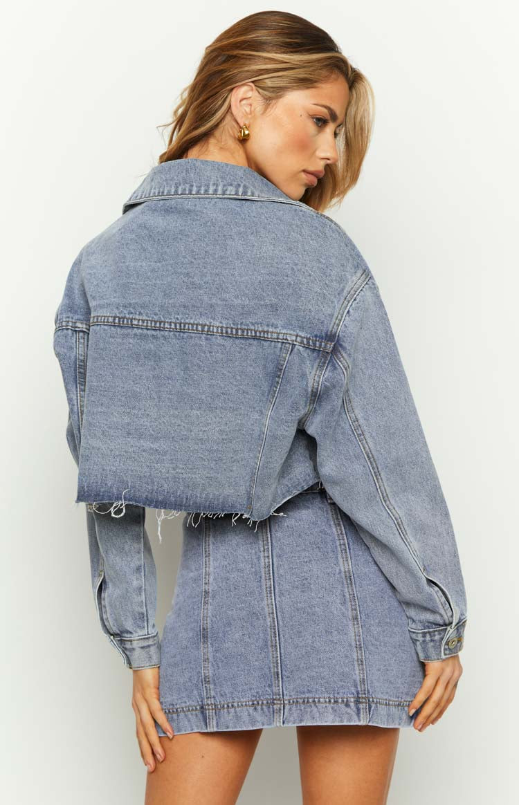 Close-up of the button-front closure and flap cargo pockets on a mid-wash denim mini skirt