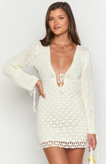 White crochet mini dress with a deep V-neckline, tie-front detail, and long sleeves with tie cuffs