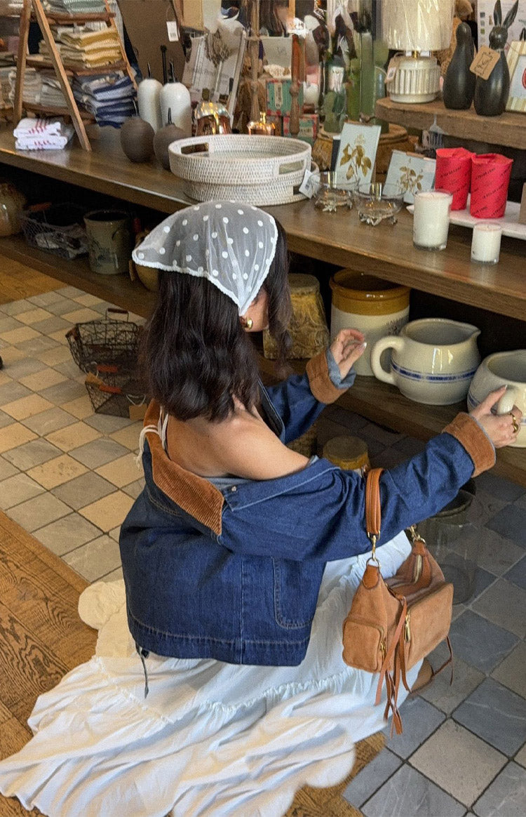 Rear view of an oversized mid wash denim jacket with brown cord trim on the cuffs and collar