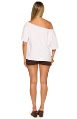 Rear view of the white boxy tee, showing the wide neckline pulled off one shoulder and its relaxed fit